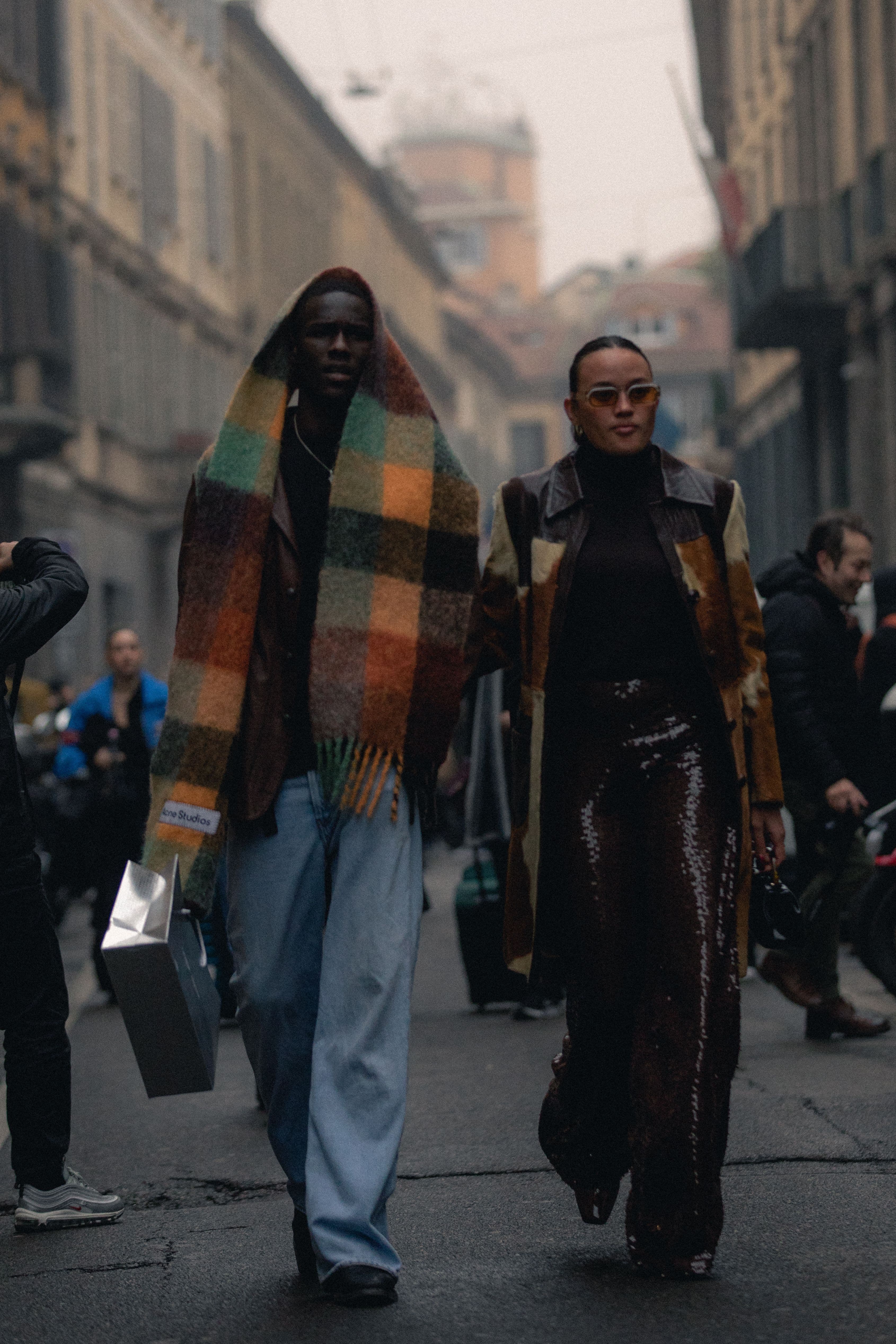 A stylish man and a woman walking.